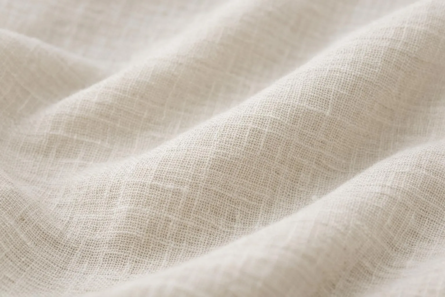 Close-up of natural linen fabric texture with visible weave structure in soft daylight, showing the breathable and airy quality of the material used for women's summer blouses