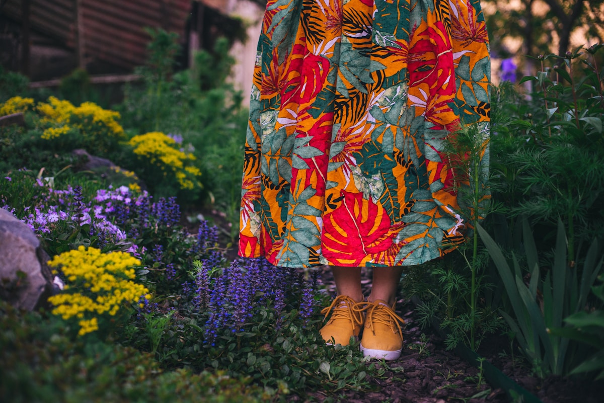 Robe colorée à motifs floraux, chaussures jaunes, jardin luxuriant.