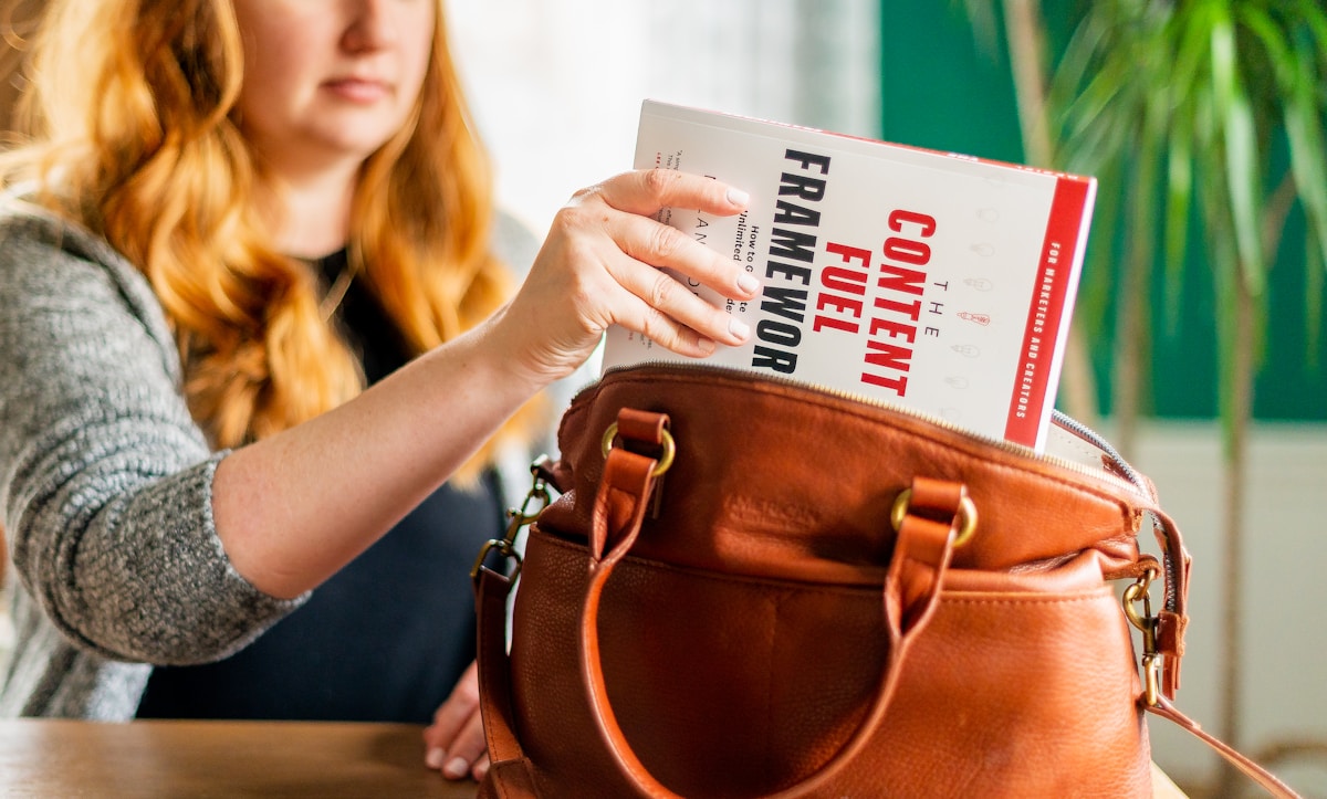 Femme avec un livre intitulé "Content Fuel Framework" dans un sac en cuir.