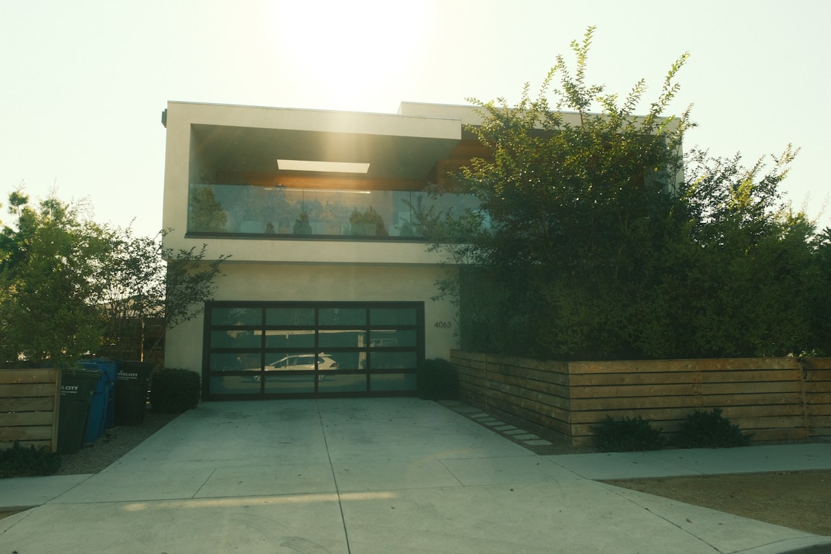 Maison moderne avec garage et végétation luxuriante.