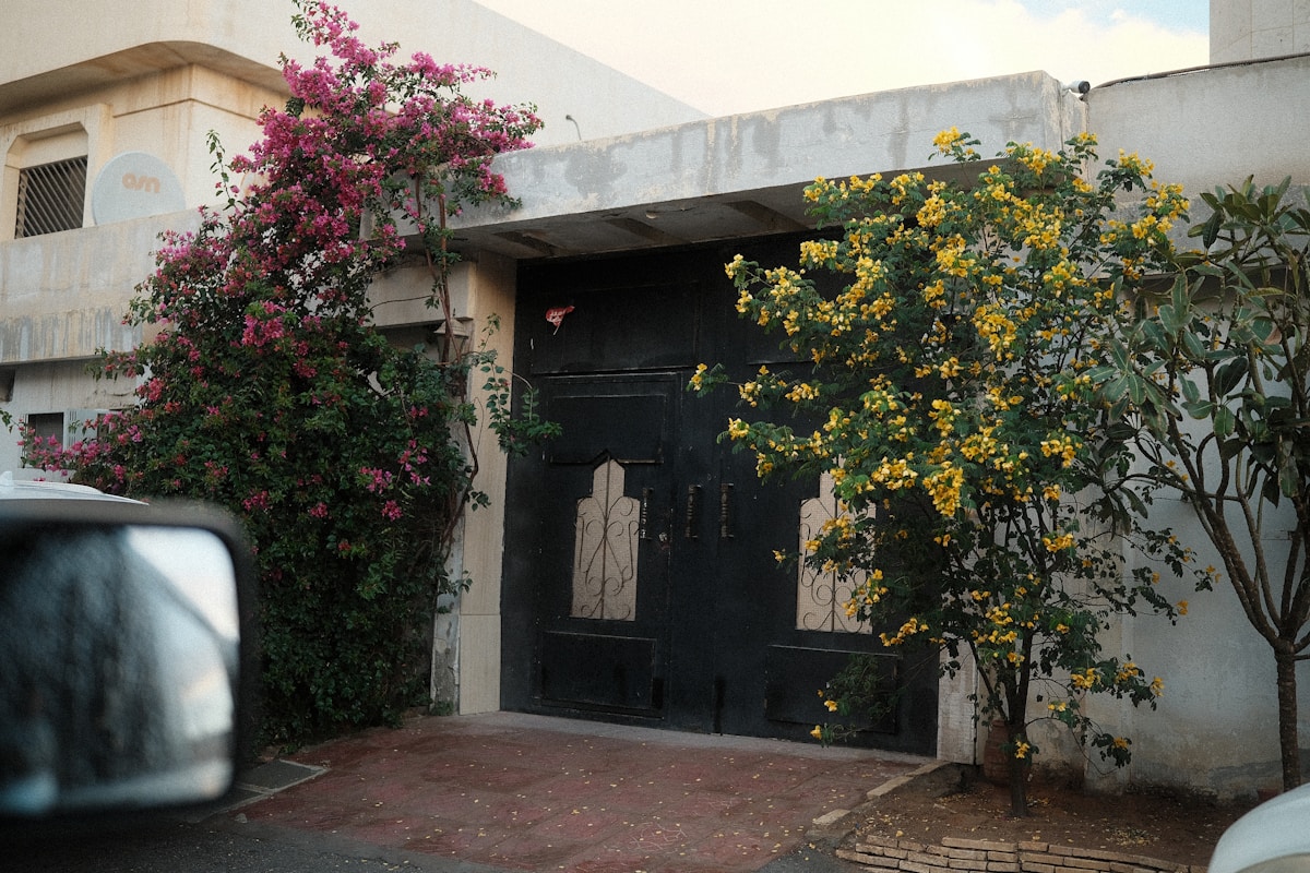 Entrée de maison avec fleurs roses et jaunes.