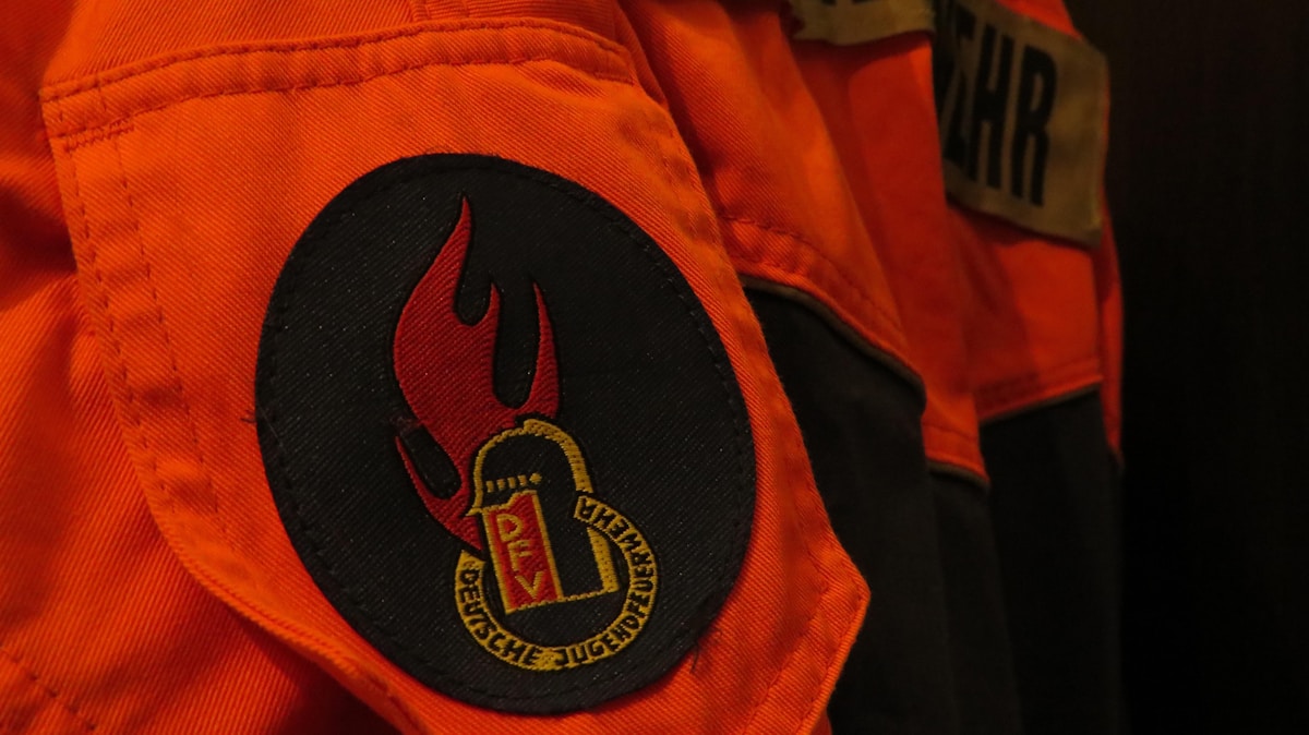 Combinaison de travail orange avec logo noir et doré.