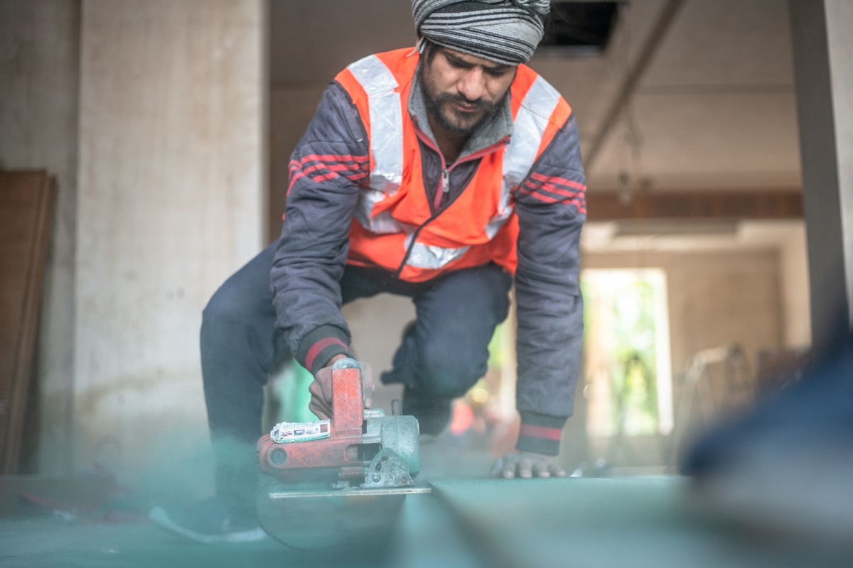 Ouvrier utilisant une ponceuse électrique sur un chantier.