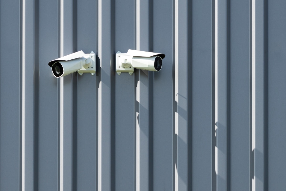 Deux caméras de sécurité blanches montées sur un mur gris.
