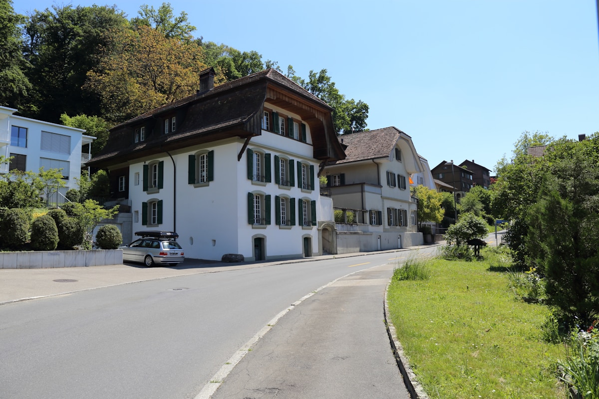 Maison traditionnelle suisse avec toit en pente et fenêtres à volets.