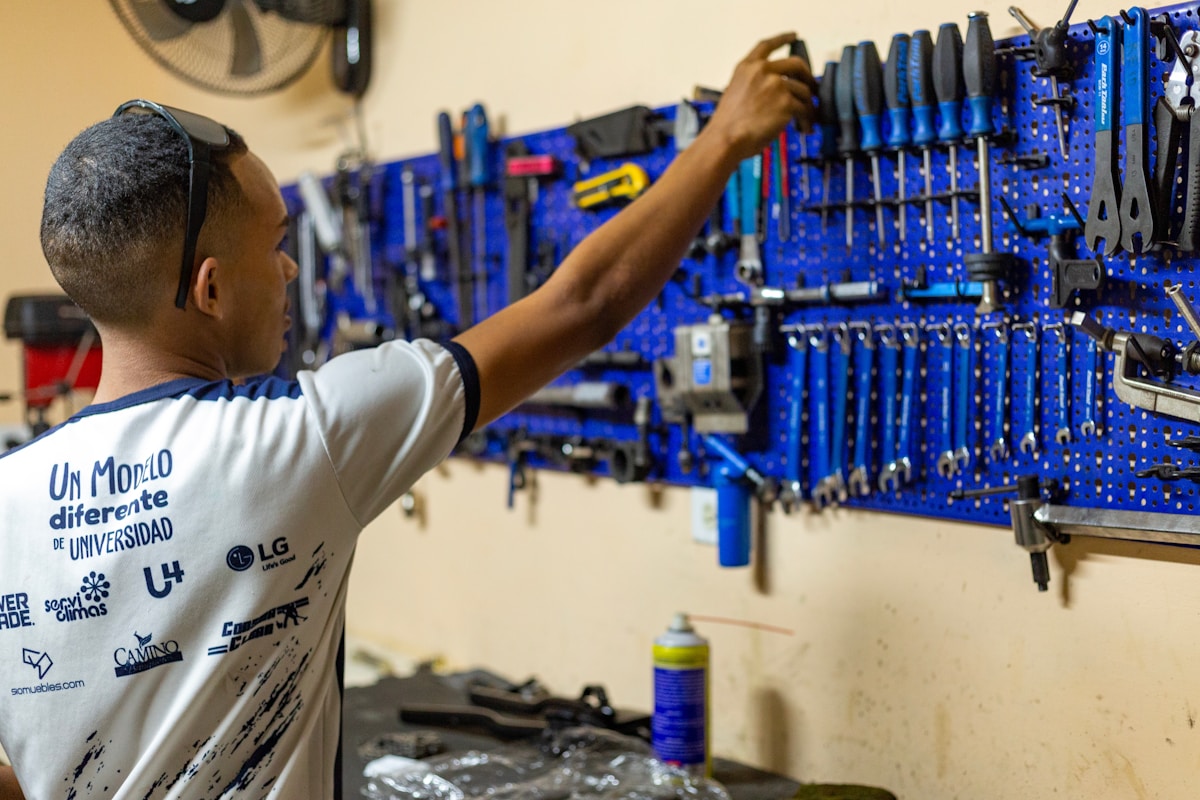 Homme travaillant dans un atelier de réparation, entouré d'outils bleus.