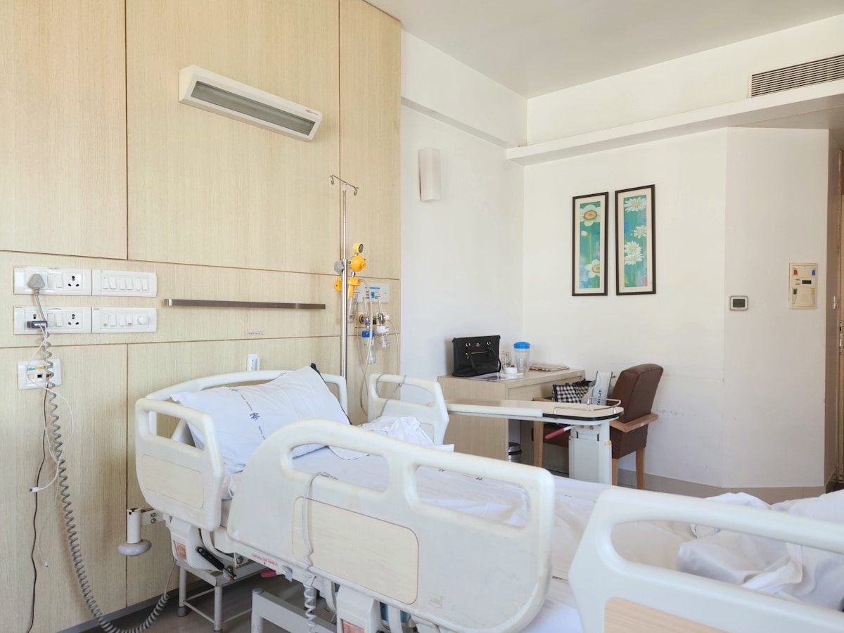 Chambre d'hôpital avec lit médicalisé, équipements et décoration murale.