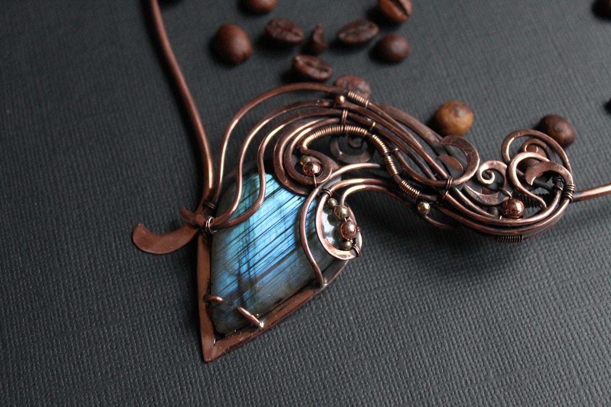 Pendentif en cuivre avec pierre bleue, motifs floraux, grains de café.
