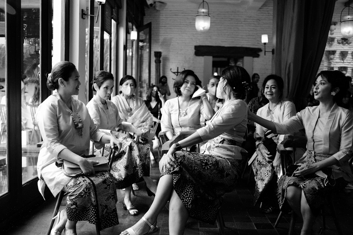 Groupe de femmes en tenue traditionnelle, assises dans un lieu intérieur.
