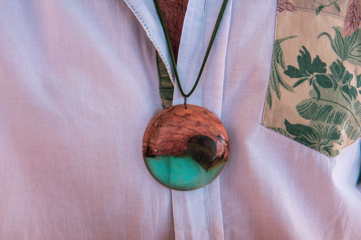Pendentif rond en bois avec motif turquoise et marron.