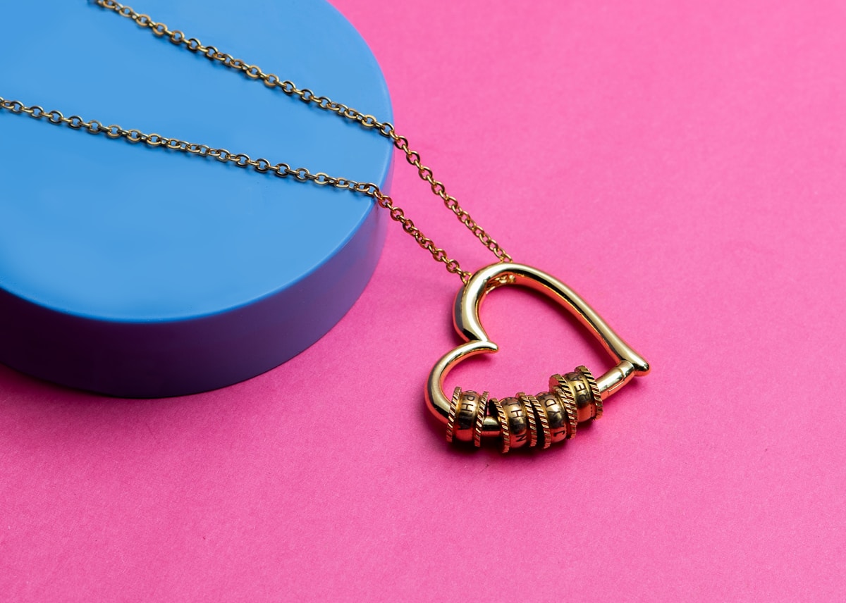 Collier doré avec pendentif en forme de cœur et anneaux.