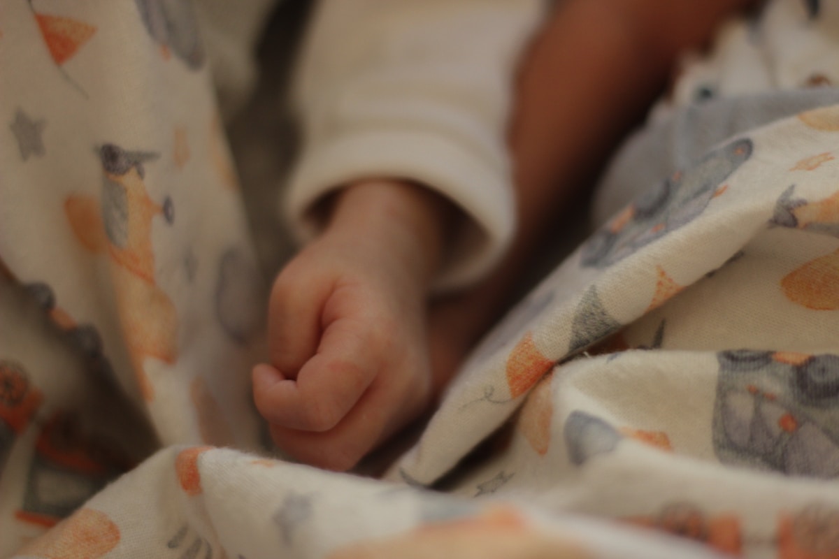 Main de bébé enveloppée dans une couverture colorée.