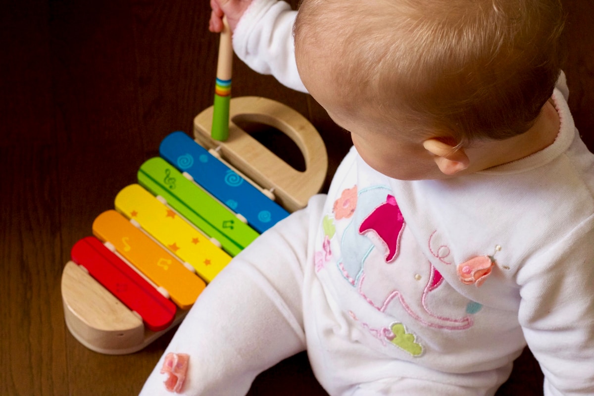 Bébé jouant avec un xylophone coloré sur une surface en bois.