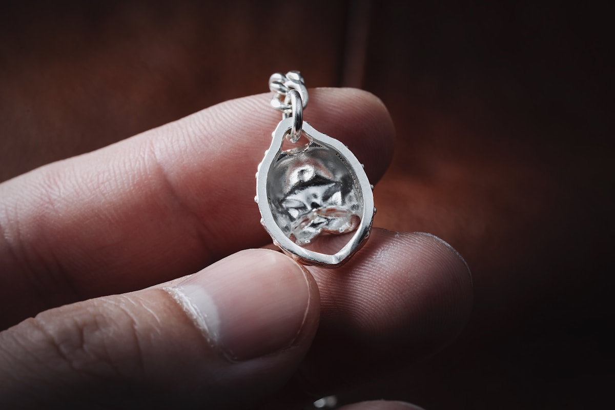 Pendentif en métal argenté avec forme abstraite.