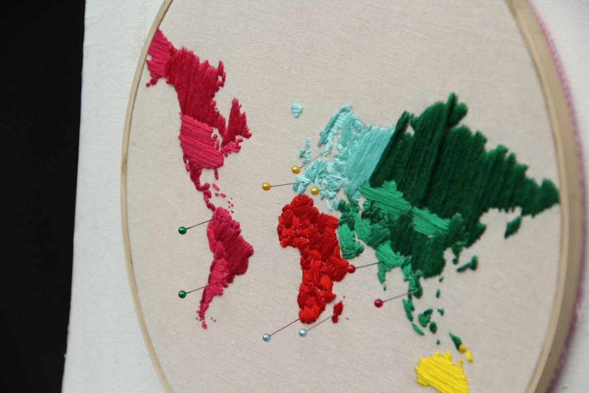 Carte du monde brodée de couleurs vives et de points épinglés.
