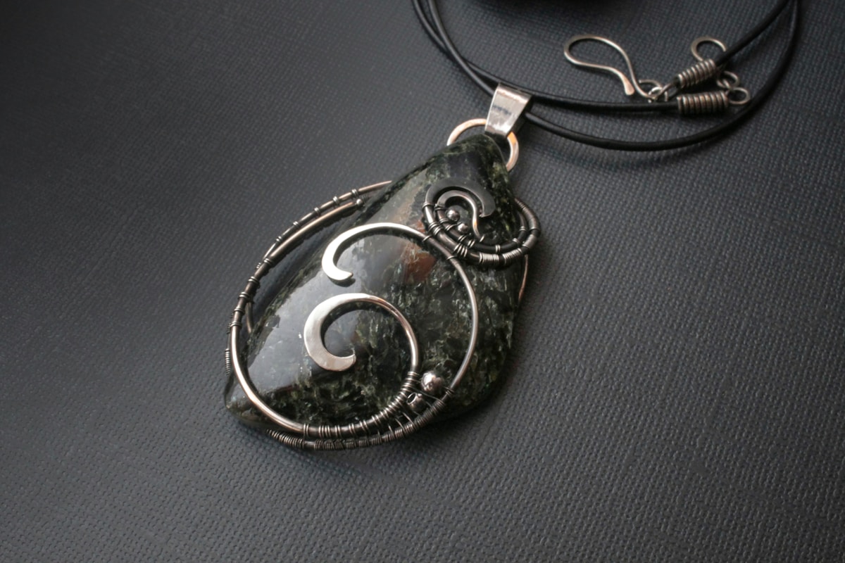 Pendentif en métal noir avec motifs spiralés.
