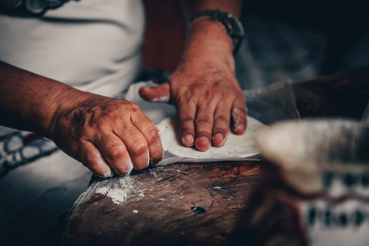 Mains calleuses d'un artisan travaillant le bois sur un établi.