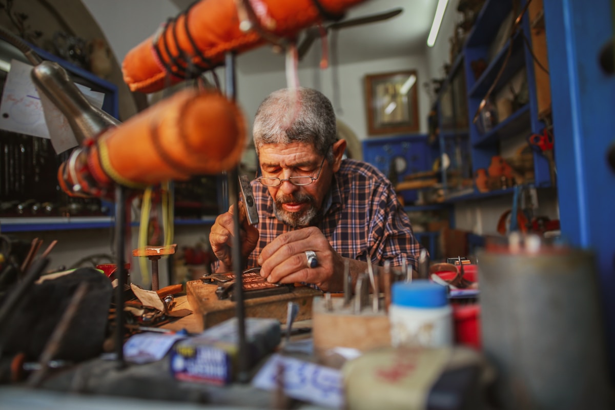 Homme âgé travaillant dans un atelier encombré.