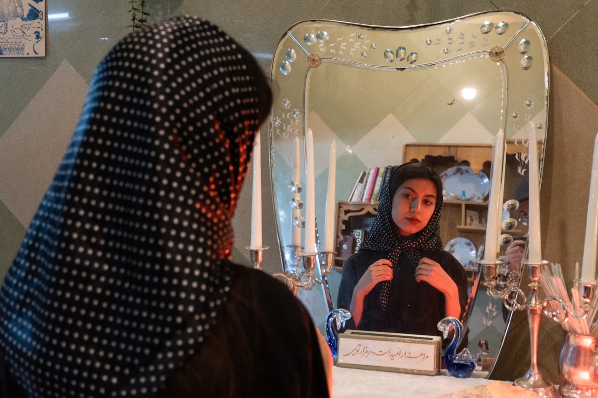 Femme voilée assise devant un miroir décoré de cristaux.