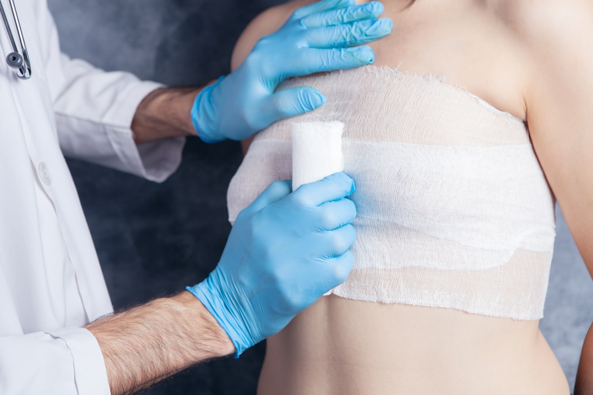 Médecin appliquant un bandage sur le torse d'un patient.