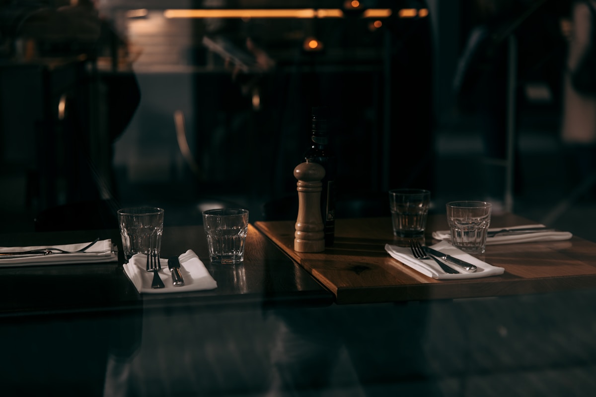 Table sombre avec verres, couverts et bougeoir.