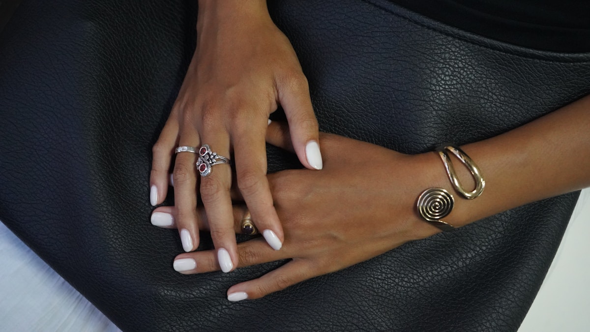 Mains féminines ornées de bijoux élégants sur un fond sombre.
