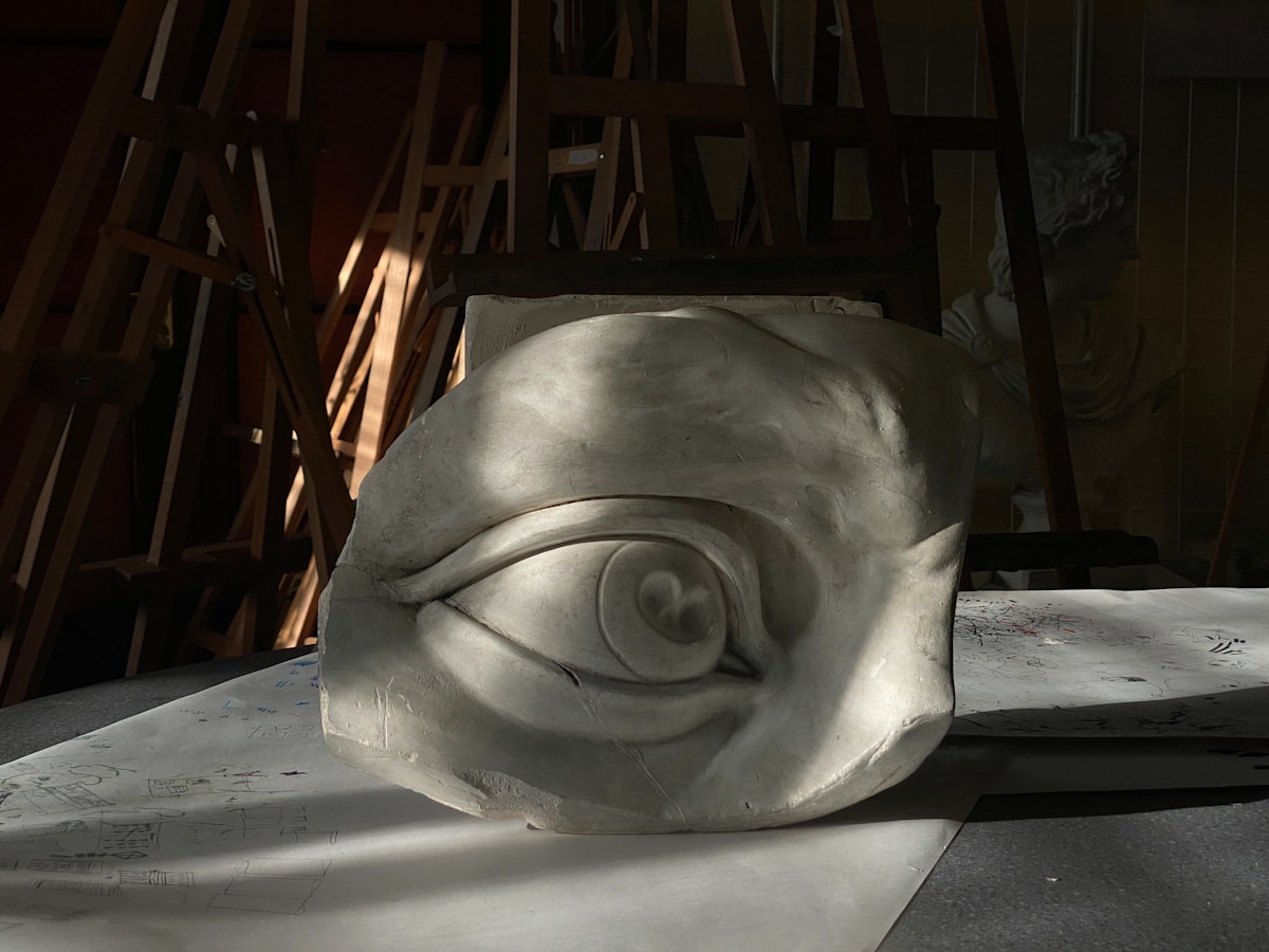 Sculpture en plâtre d'un œil géant dans un atelier sombre.