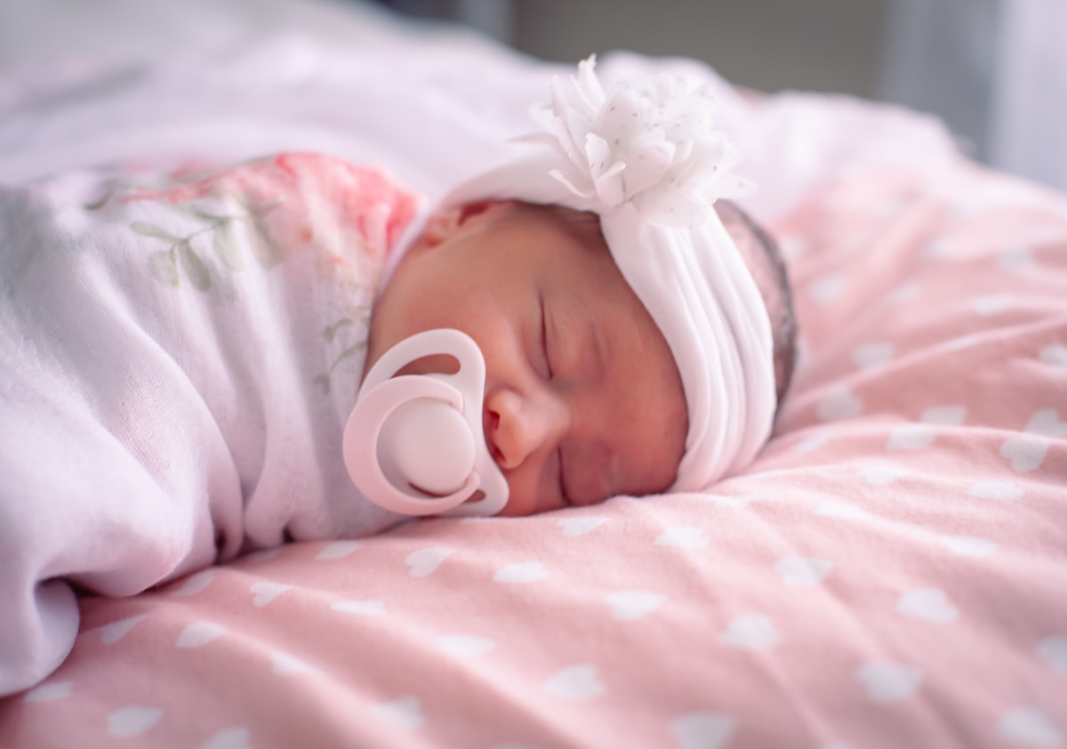 Bébé endormi dans une couverture rose avec un sucette.