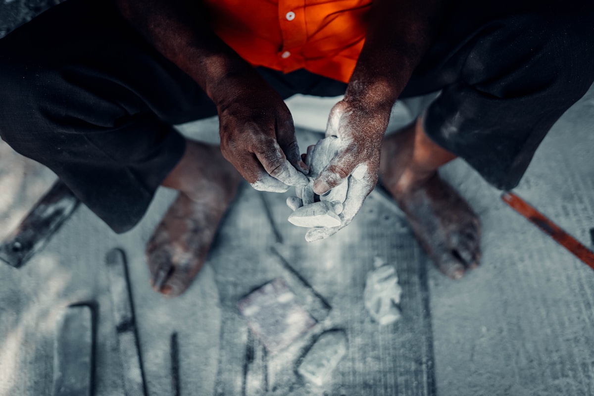 Mains calleuses d'un travailleur manipulant des outils sur un chantier.