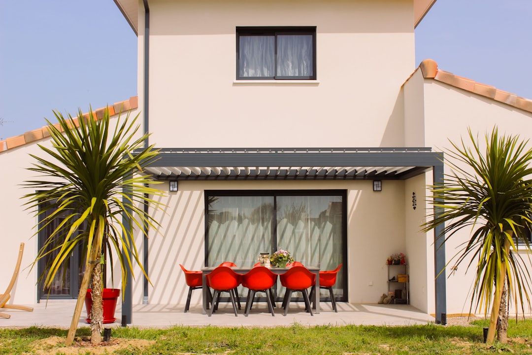 portail coulissant motorisé - a white house with a red table and chairs