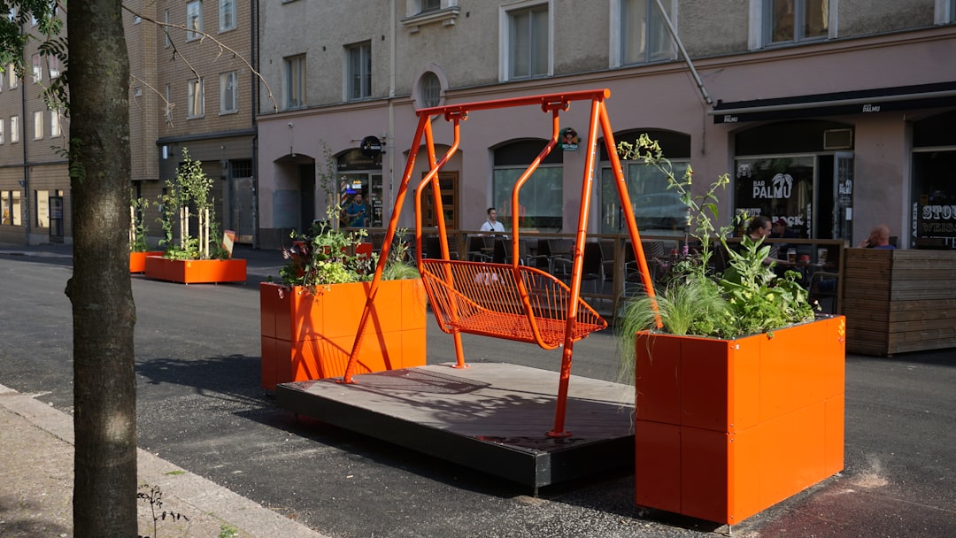 jardinière acier corten sur mesure - Orange swing set with planters on a city street