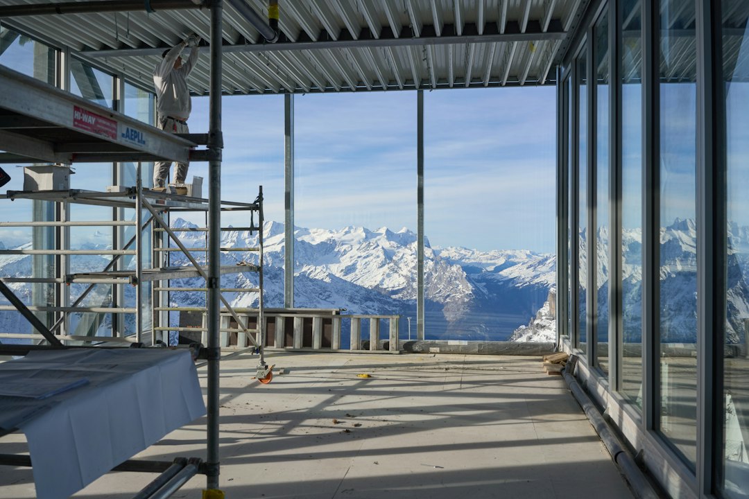 Interne de chantier avec fenêtres sur montagne, illustrant gestion de projet métallerie sur-mesure en Suisse.