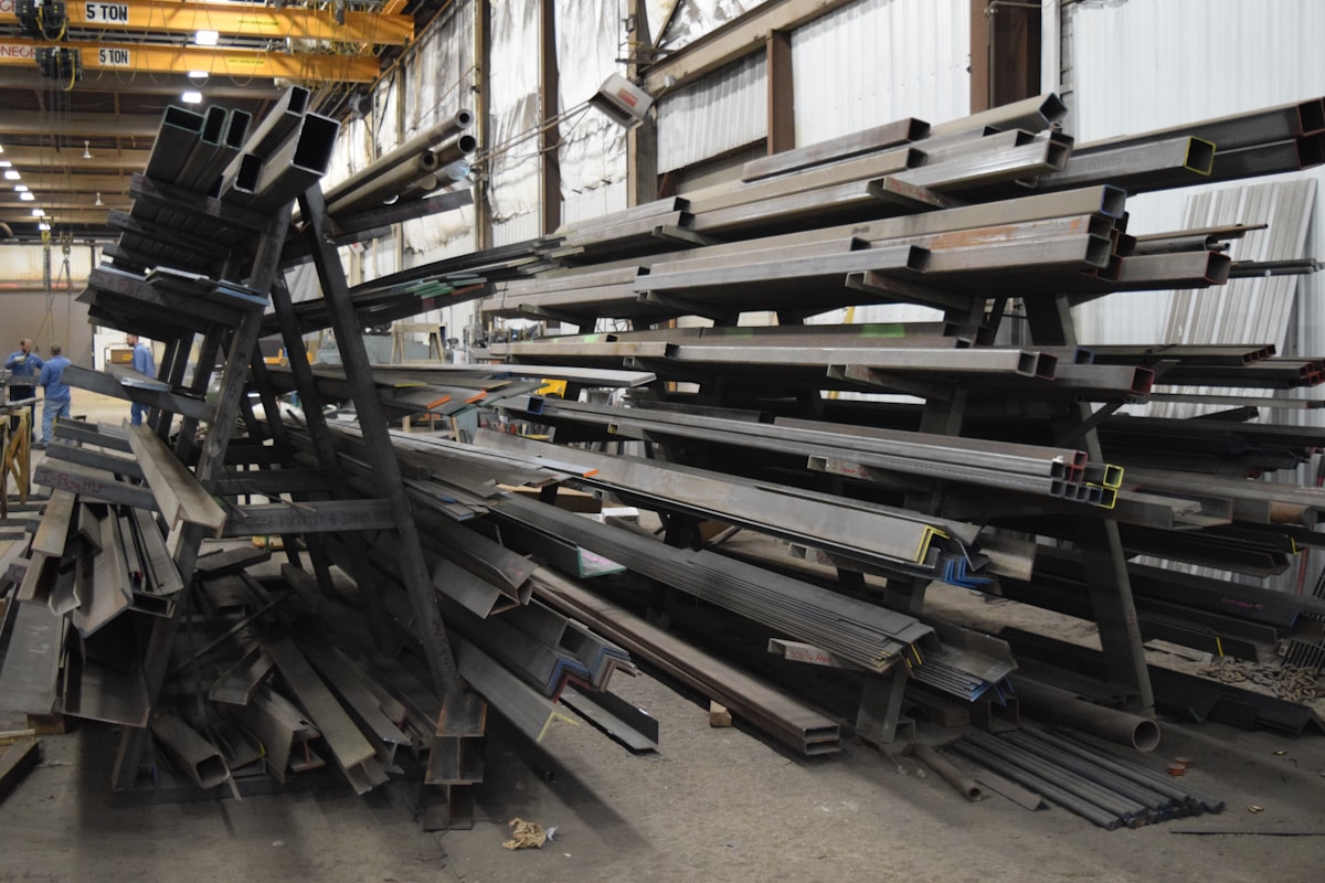 Entrepôt industriel rempli de poutres et de tuyaux métalliques.