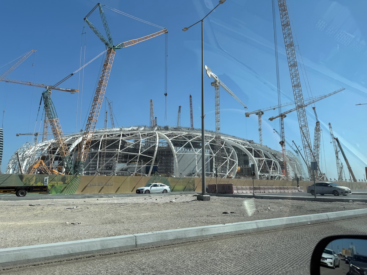 Stade de football en construction avec de nombreuses grues et échafaudages.