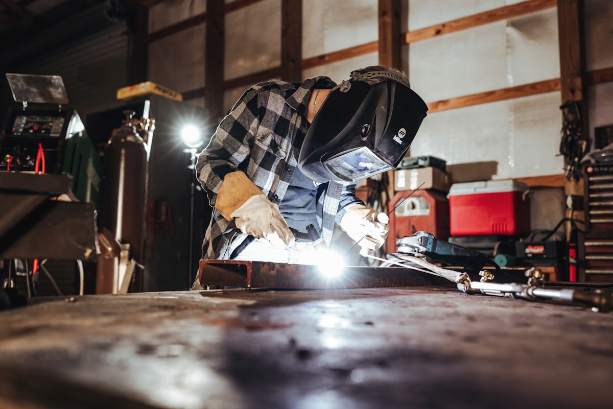 Soudeur travaillant dans un atelier avec équipement de protection.