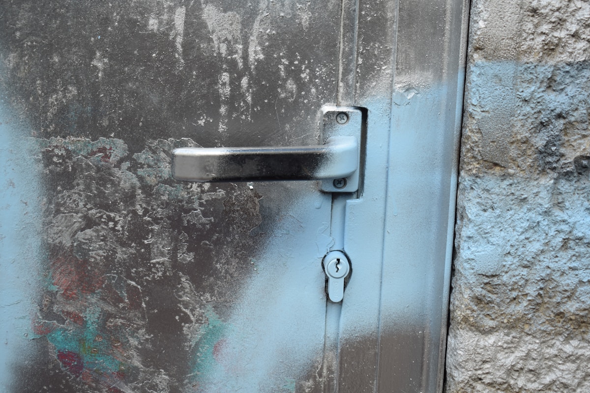 Poignée de porte métallique rouillée sur un mur délabré.