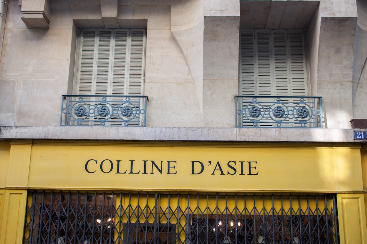 Façade d'un bâtiment avec fenêtres à volets et enseigne "Colline d'Asie".