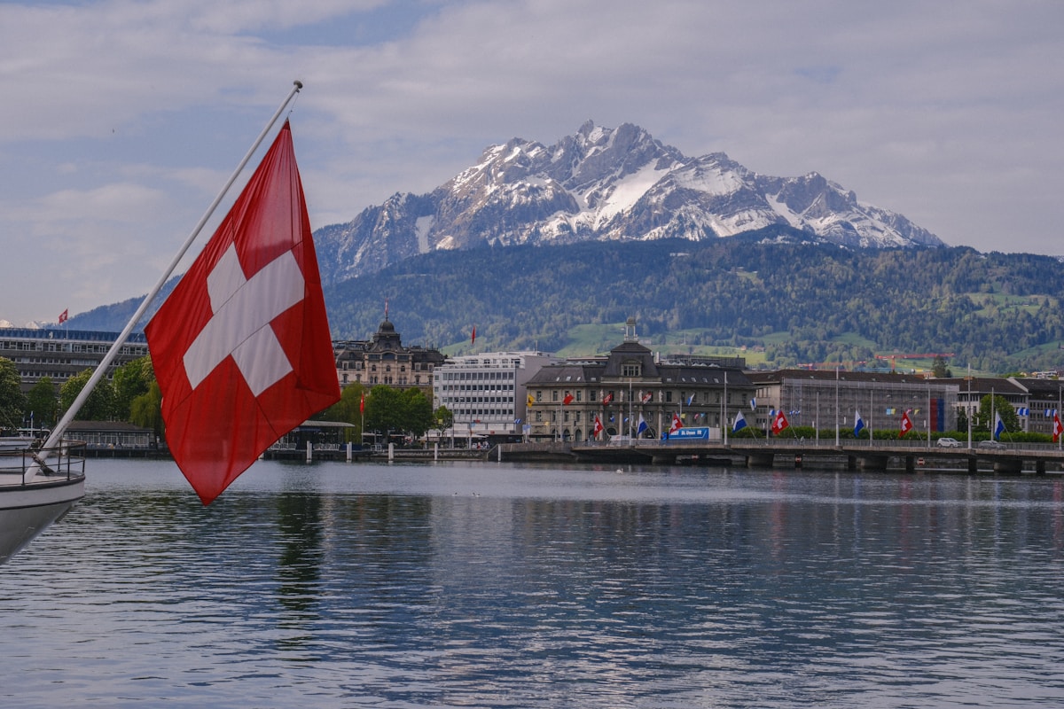 Paysage montagneux suisse avec drapeau national et bâtiments historiques.