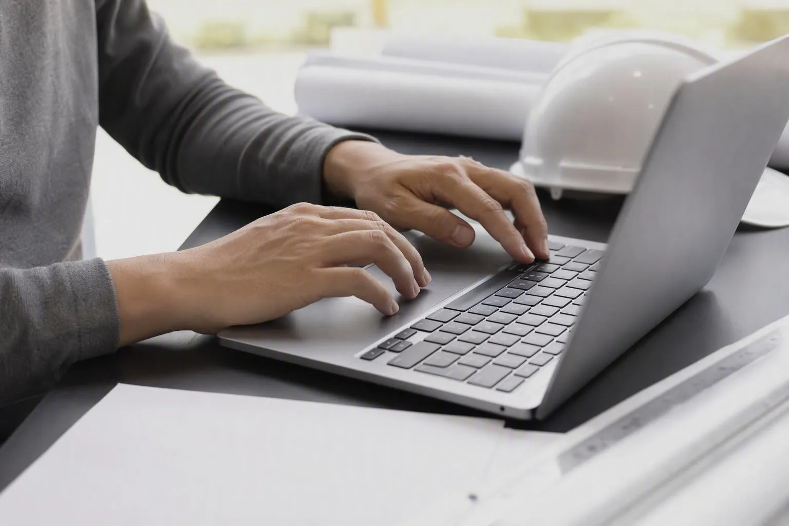 Mains tapant sur un clavier d'ordinateur portable dans un bureau.