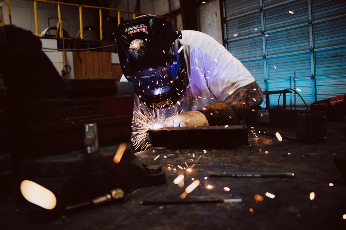 Soudeur travaillant avec un équipement de soudage dans un atelier industriel.