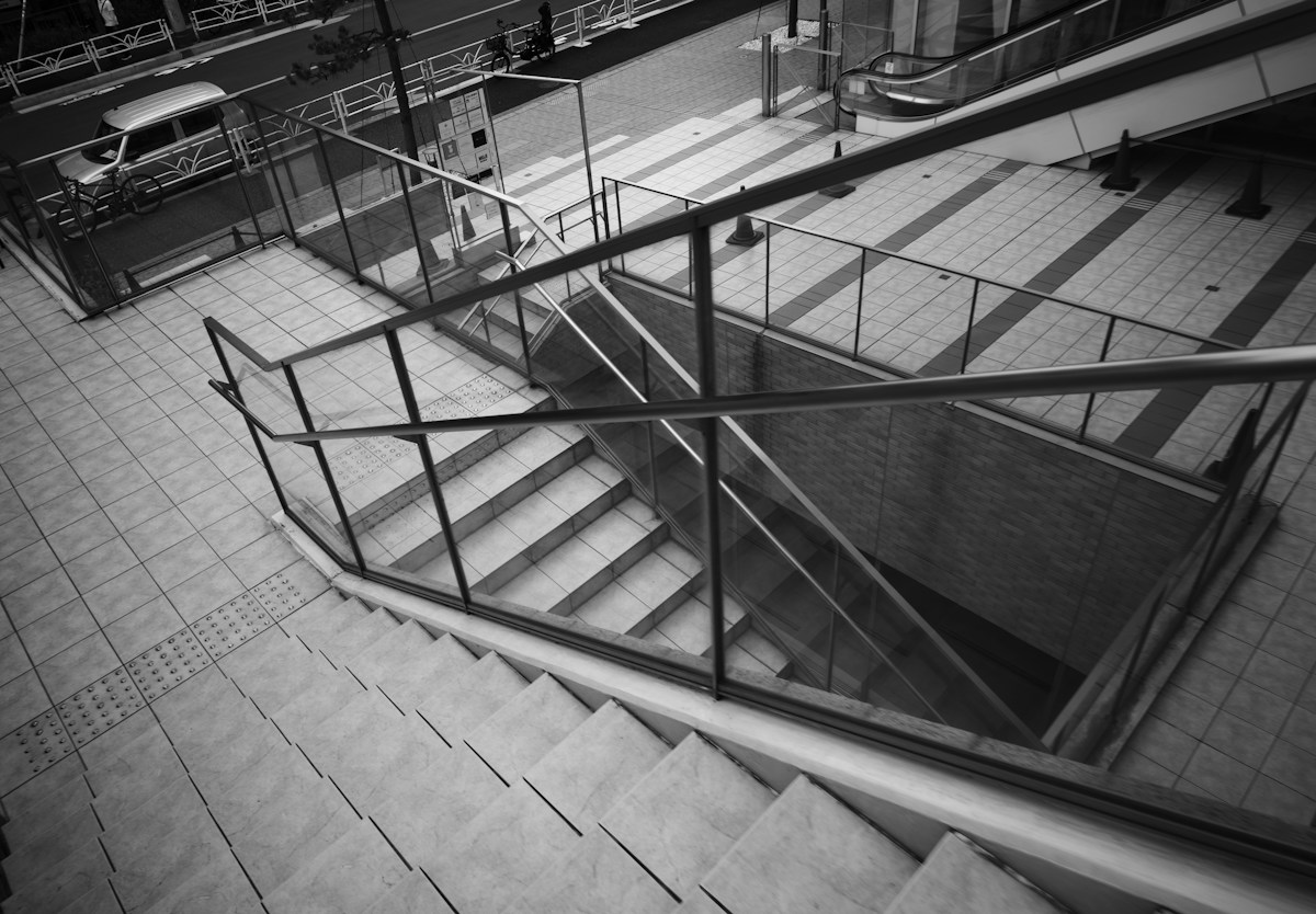 Escalier urbain vitré descendant vers une station de métro en plein air