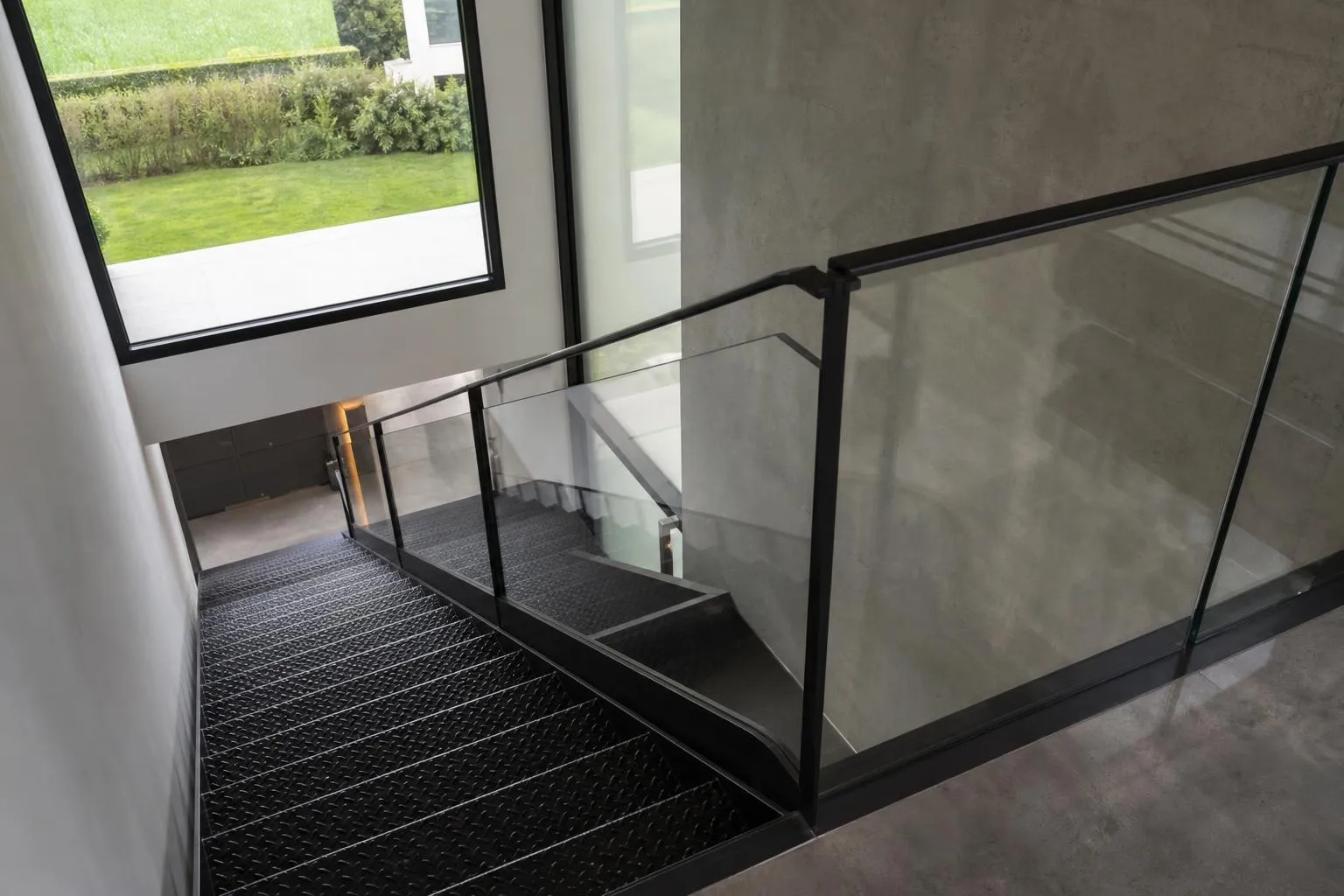 Escalier en verre et métal avec vue sur le jardin.