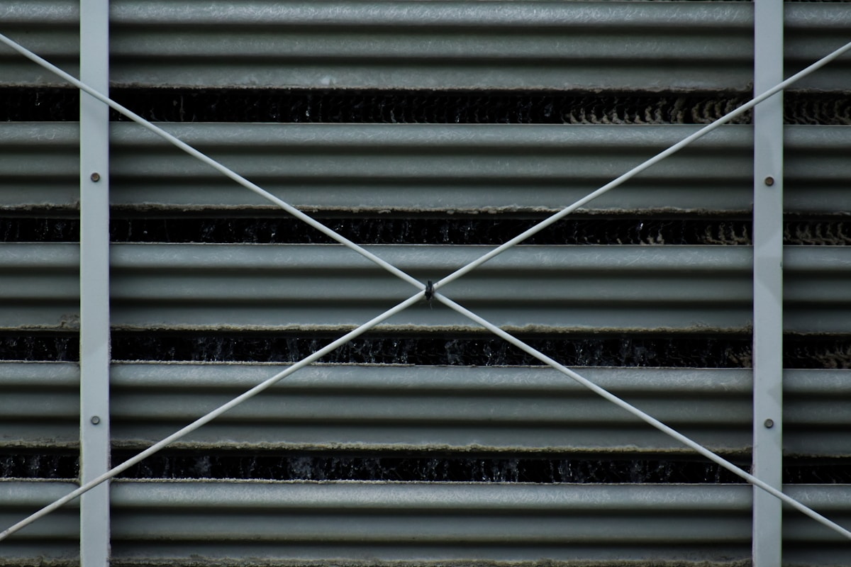 Grille métallique grise avec motif croisé et lignes horizontales.