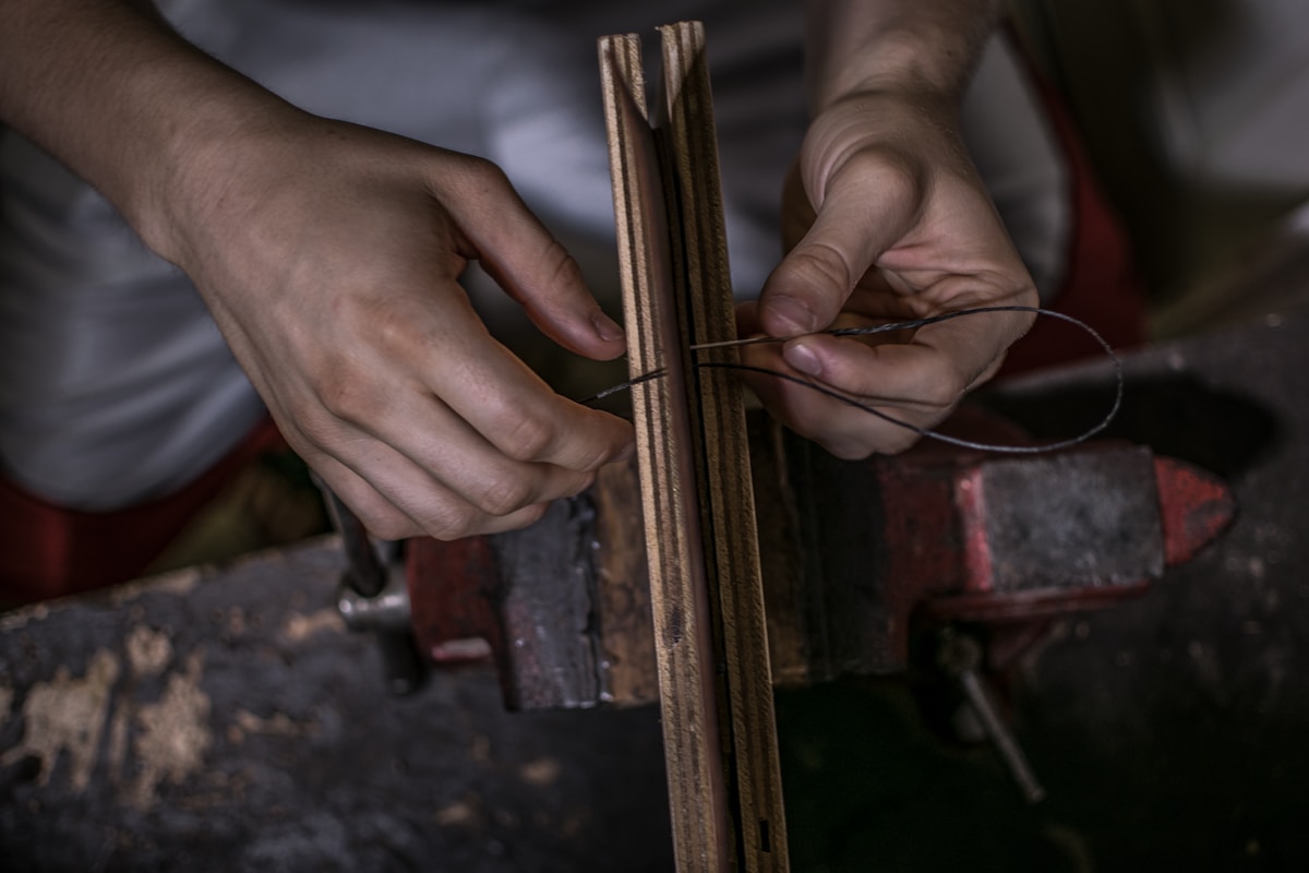 Mains travaillant le bois avec des outils artisanaux.