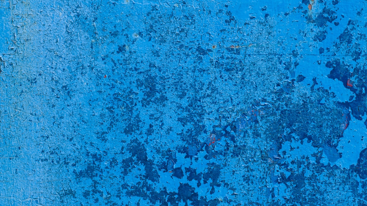 Texture bleue décolorée et écaillée sur une surface métallique.