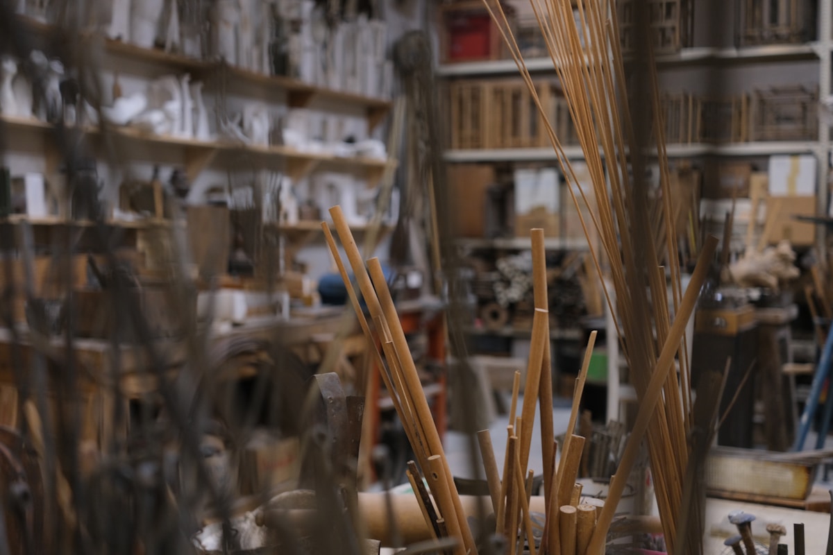 Atelier d'artiste encombré, avec des pinceaux et des étagères remplies d'objets.