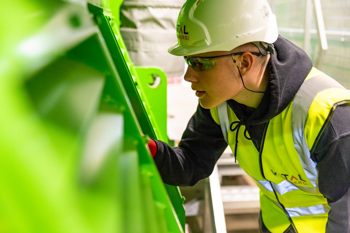 Ouvrier en uniforme vert travaillant sur une machine industrielle.