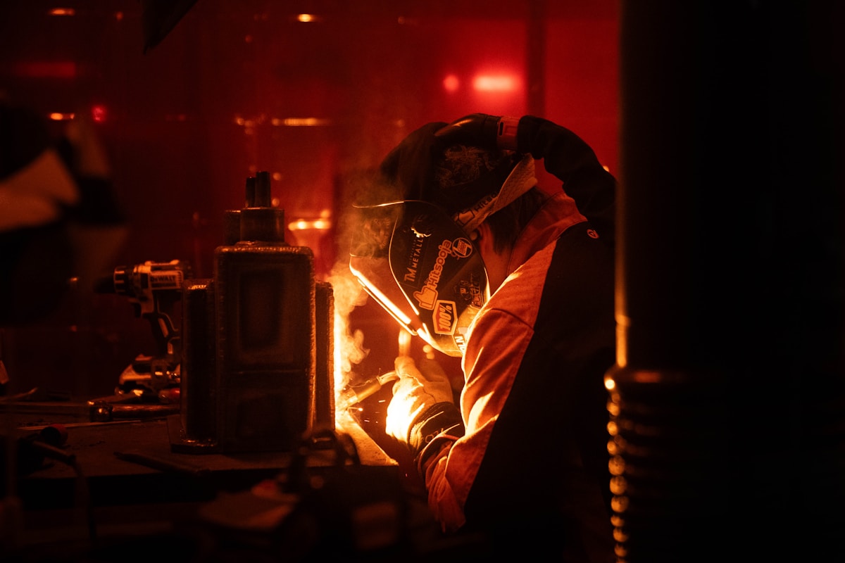 Soudeur travaillant dans un environnement sombre et rougeoyant.
