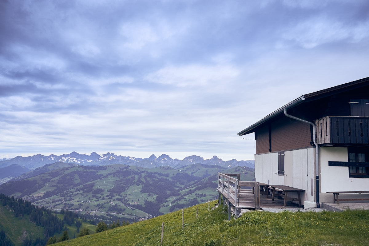 Paysage montagneux avec chalet en bois sur une colline.