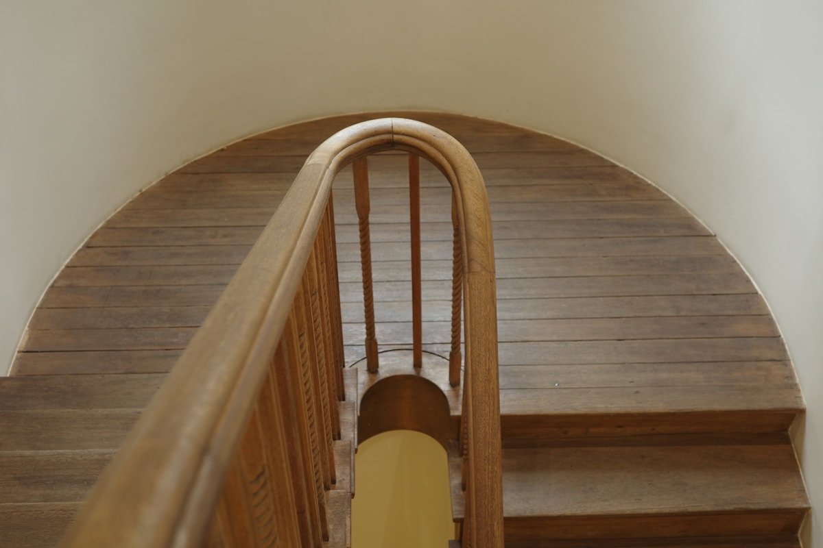 Escalier en bois avec arche et barreaux décoratifs.